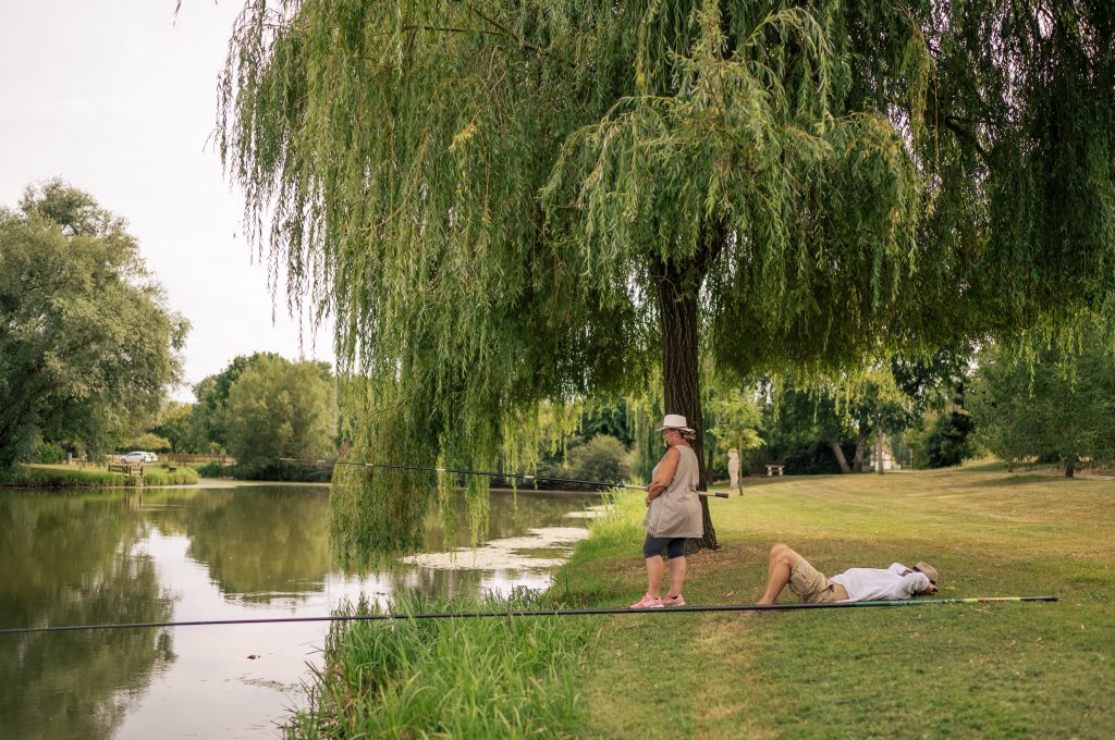 Pêcheuse avec homme qui est allongé à côté pour la sieste au bord de l'eau
