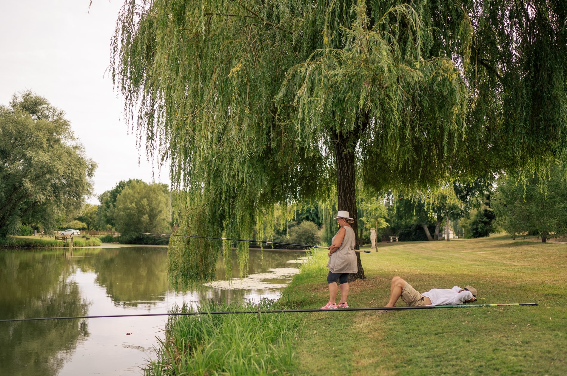 Pêcheuse avec homme qui est allongé à côté pour la sieste au bord de l'eau