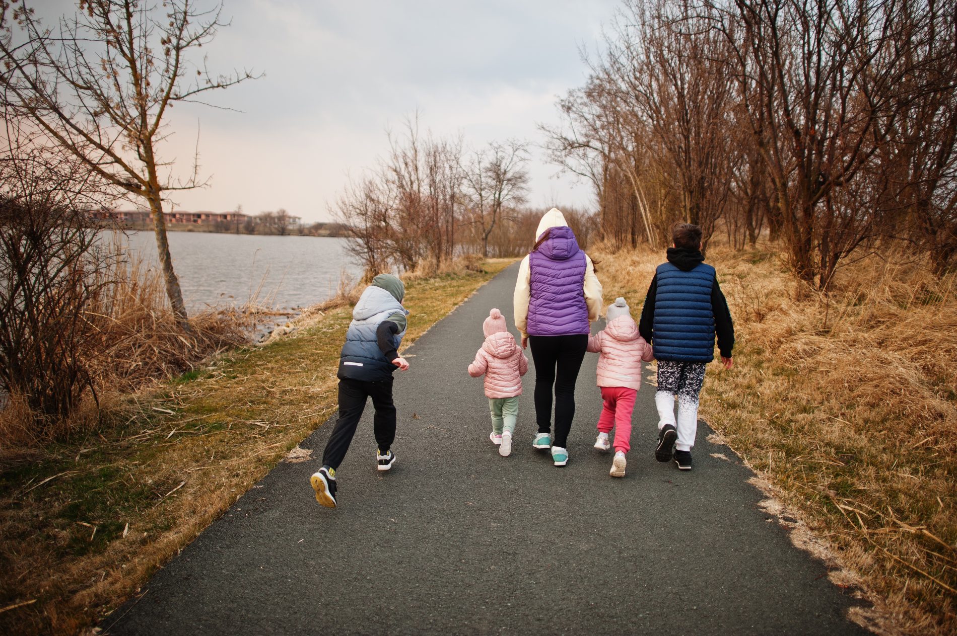Idée sortie en famille avec enfants et parents se baladant au bord de l'eau, de dos